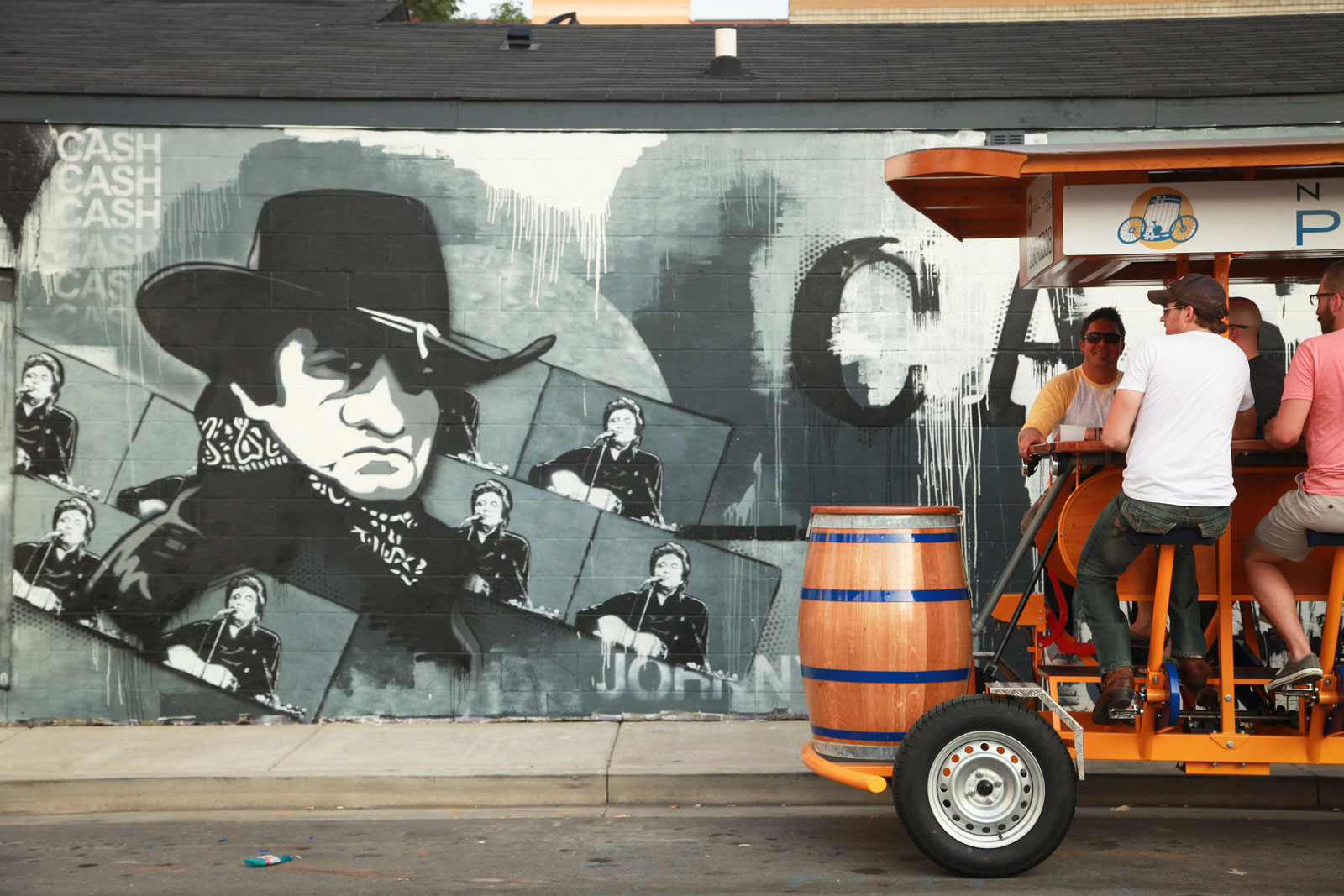 Photo of a Pedal Tavern boat in the foreground, with a Johnny Cash mural in the background.