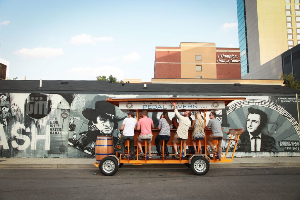Wide photo of a Nashville Pedal Tavern boat in front of a Johnny Cash mural