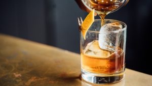 whiskey cocktail being poured into rocks glass with ice