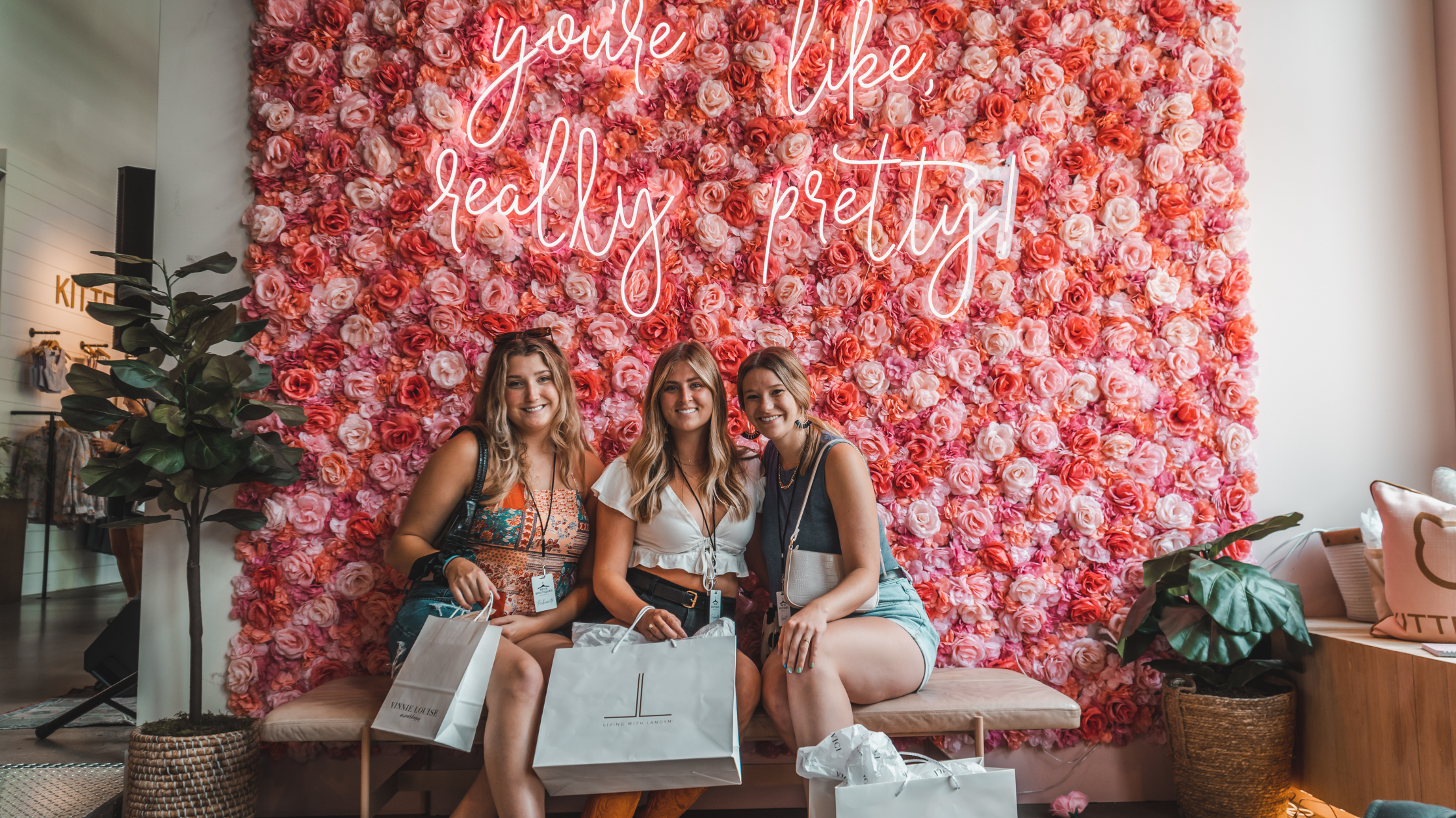 3 women shopping at Kittenish in Nashville, sitting in front of a pink photo background that says you're like really pretty